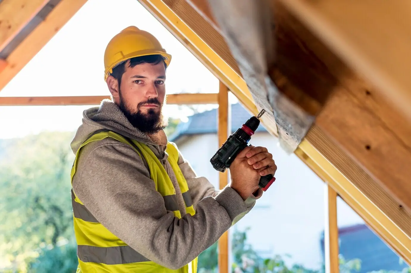A man grips a hammer drill and looks away.